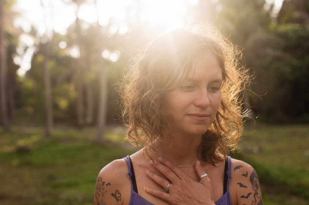 woman appears relieved, standing outside with the sun shining on her.